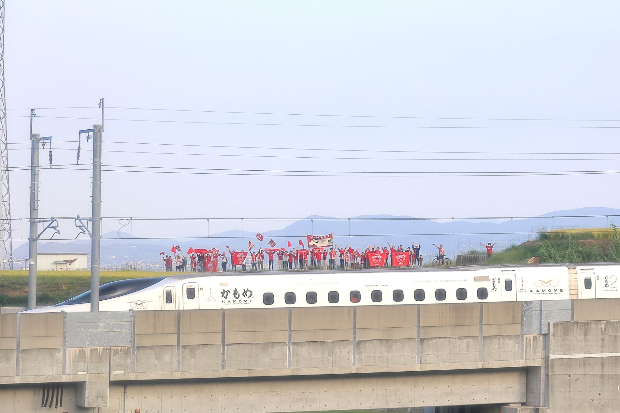 西九州新幹線かもめに向かって線路沿いから手を振る参加者たち