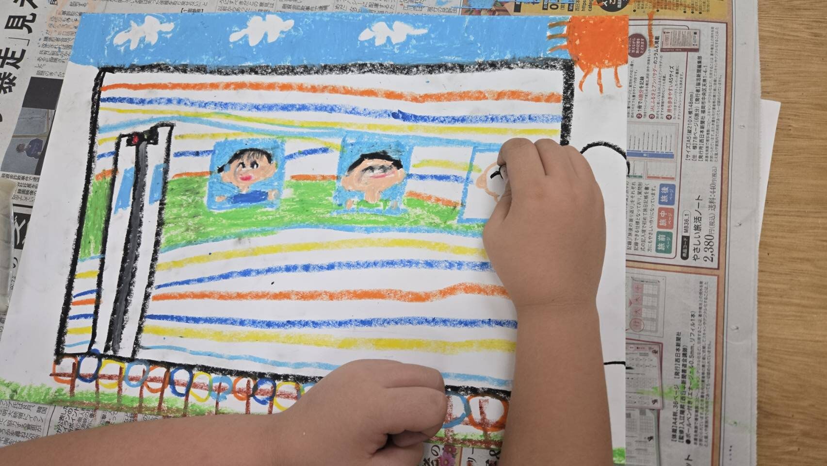 子どもがクレヨンで電車の絵を描いている手元